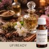 Flakon perfum wśród przypraw, kwiatów i olejków na drewnianym tle